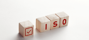 Wooden blocks spelling 'ISO' with a red checkmark on one block, representing affordable ISO auditing services and certification processes in Florida.